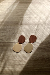 Pair of gilden statement earrings, illuminated by sunlight. Selective focus.