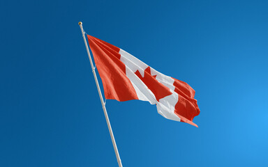 Isolated Canada flag waving in the wind against blue sky background. Canada national flag close up