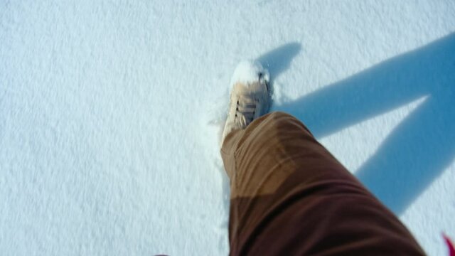 Hiking shoes POV walk on snow on winter hike, explorer boots leave footprints on fresh snow. Walking or hiking during winter season in mountains or forest. Winter outdoor activities