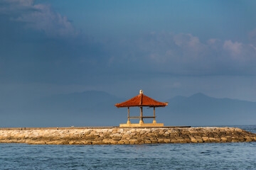 A single hut in the middle of the sea surrounded by blue water and evening sky with scenic view during vacation in Bali