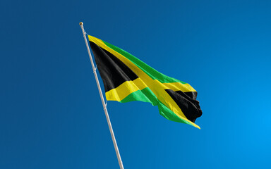 Isolated Jamaica flag waving in the wind against blue sky background. Jamaica national flag close up