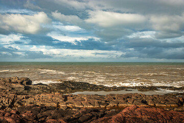 rocky sea beach with crashing waves at morning from flat angle