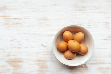 Free-range organic brown eggs in bowl on wooden background, copy space