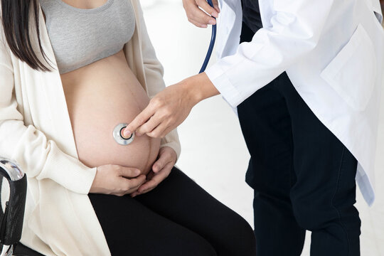 Cropped image of pregnant woman visit doctor in hospital. Doctor examining  and checking her by stethoscope and listening baby heartbeat. Concept of pregnancy, health care and medical service.