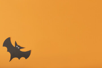 Halloween holiday concept. paper bat with eyes on orange backgound with copy space