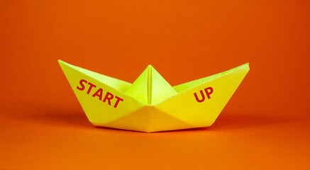 Image of origami boat with words 'start up'. Over orange background with copy space. Business concept.