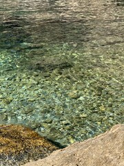 Crystal clear water of Adriatic sea. Pebble seabed. Beautiful sea stones. Refreshing  transparent sea water. Summer in Montenegro. Scenic cobblestones. Clean waters. Relax on the sea shore
