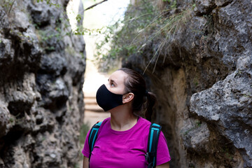 Caucasian girl with mask on her face doing trekking through nature