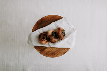 Three sourdough bun flat lay with poppy seed and sesame on a napkin on a wooden stool