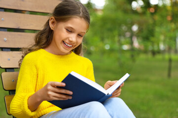 Fototapeta premium Happy little girl reading book in park