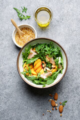 Grilled peach salad with rucola, jamon and almonds. Bowl with fruit salad on gray marble background