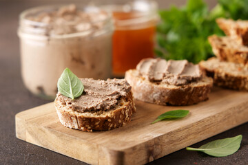 Fresh homemade liver pate on bread. Traditional French meat appetizer.  Brown background with empty space - obrazy, fototapety, plakaty
