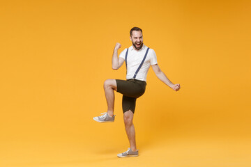 Fototapeta na wymiar Full length side view portrait of joyful happy young bearded man 20s wearing white shirt suspender shorts posing clenching fists doing winner gesture isolated on bright yellow color background studio.
