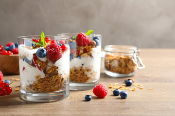 Tasty dessert with yogurt, berries and granola on wooden table