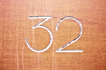 Number 32, thirty-two, stylish digits on brown background.