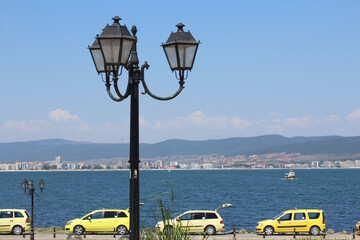 Row of yellow taxi cars on the seashore, a vintage street light on the foreground