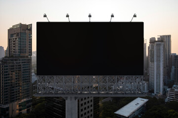 Blank black road billboard with Bangkok cityscape background at sunset. Street advertising poster, mock up, 3D rendering. Front view. The concept of marketing communication to promote or sell idea. © VideoFlow