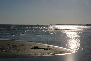 Beach in sunset. The water and small ripples are shining inder sun. The photo is taken in Pärnu, Estonia.