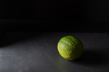 fresh dark green lemon, lime isolated on dark background