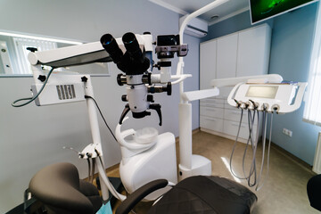 Dentistry, medicine, medical equipment and stomatology concept. Interior of new modern dental clinic office with chair and microscope.