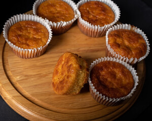 Golden sweet homemade and freshly baked cornbread muffins for lunch on wooden tray, close up.   Dark background