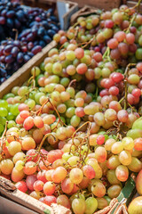 Bunches of different varieties of grapes on the counter of the farmers ' market. Grapes are being prepared for sale. Bunches of grapes are collected in boxes for sale. Background
