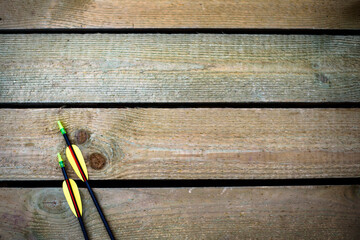 two arrows for a bow lie on a wooden background with space for inserting text