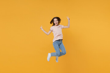 Fototapeta na wymiar Full length portrait of cheerful funny young woman 20s wearing pastel pink casual t-shirt posing jumping showing victory sign looking camera isolated on bright yellow color wall background studio.