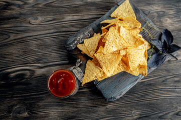 nachos and tomato sauce on a wooden background. Mexican national snack top view. copy space