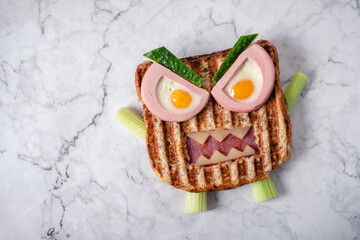 Fun Halloween monster sandwich with slice meat sausage, eggs and cheese on plate