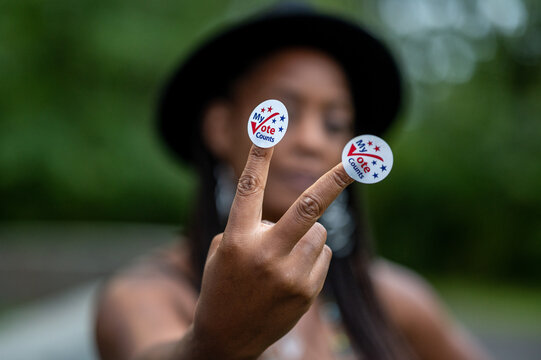 Black Woman Holding A Pair of My Vote Counts Stickers
