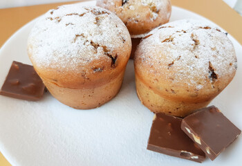 Three cupcakes on white dish with pieces of chocolate. Muffins with chocolate. 