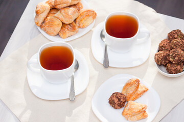 Fresh homemade sugar cookies with tea on white table with sun lights. Good morning or day concept.