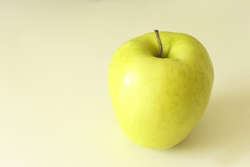 One green apple on white surface.