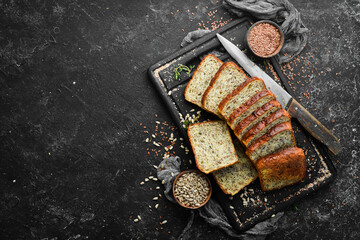 Rye bread with sunflower and flax seeds. Top view. Black stone background, rustic style.
