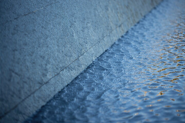 Background with running water. An element of a street fountain. Water running down the wall. Selective focus.