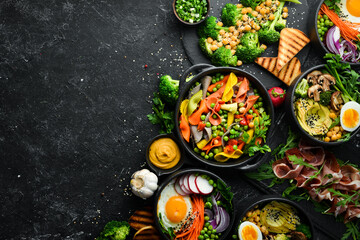 Food: pasta, pork ribs, avocado, Buddha bowl and beet salad on a black stone background. Top view....
