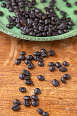 Top view of green plate with defocused coffee beans, on rustic wooden table with coffee beans, in vertical