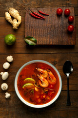 Tom yam soup with shrimp and lime in a light plate on the table ginger, lime and mushrooms.