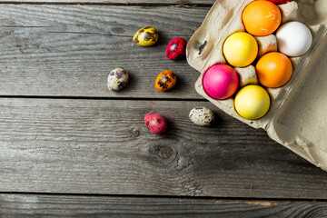 Dyed easter eggs in cardboard box on wooden background.