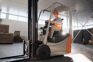 Delivery concept. Driver at warehouse in forklift - obrazy, fototapety, plakaty