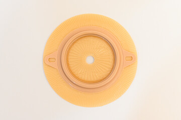 Yellow colostomy disk on white background. Part of stoma set.