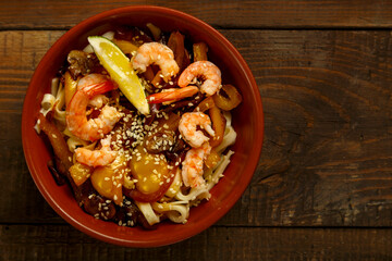 udon with mushrooms and shrimps in a clay plate on the table.