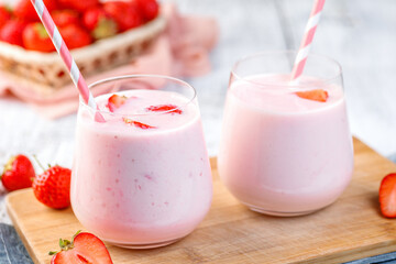 Glass with strawberry smoothie or milkshake on wooden table. Summer drink.