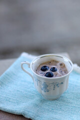 Banana and blueberry vegan nice cream, served in a vintage porcelain cup. Selective focus.