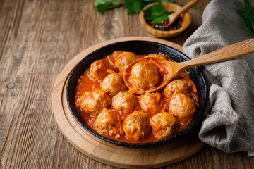 Meatballs in a pan in sweet and sour tomato sauce