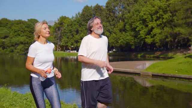 Happy caucasian old couple jogging running outdoors in park