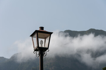 Fototapeta na wymiar Vintage electric lamp. High mountain and cloudy sky in the background. Sao Vicente, Madeira Island. 