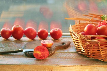 Ripe tomatoes on a wooden table, basket, cutting board for preparing healthy homemade food