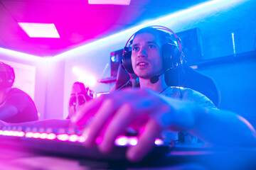 Professional gamer greeting and support team fists hands online game in neon color blur background. Soft focus, back view © Parilov